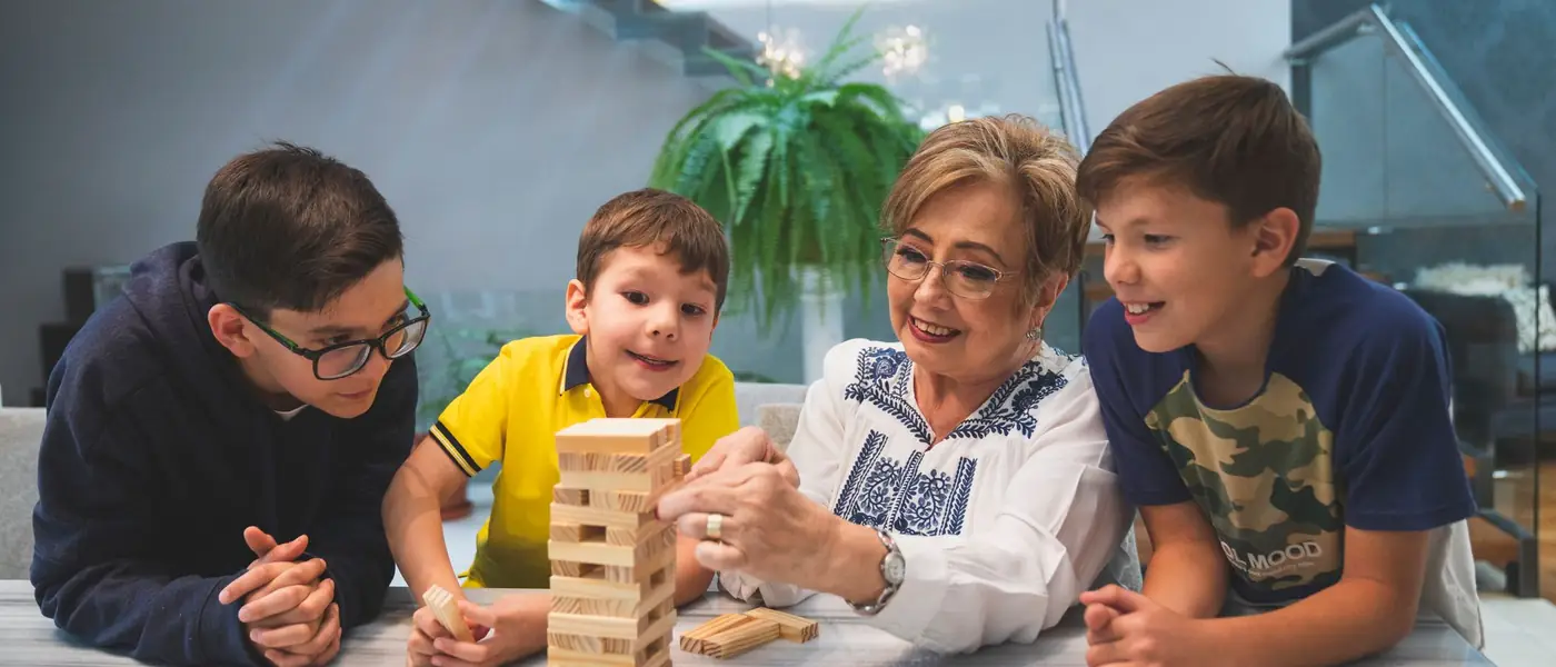 A grandmother and three grandsons stretched out on the floor playing a tower-stacking game